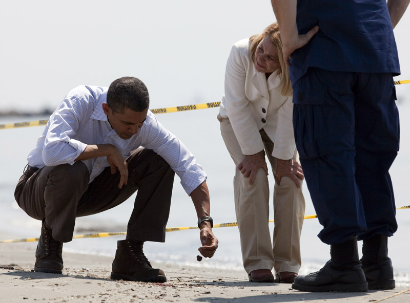 President Barack Obama, left, picks up a "tar ball" as LaFourche Parish president Charlotte Randolph, center, and U.S. Coast Guard Admiral Thad Allen, National Incident Commander for the BP Deepwater Horizon oil spill, look on during a tour of areas impacted by the Gulf Coast oil spill today in Port Fourchon, La.