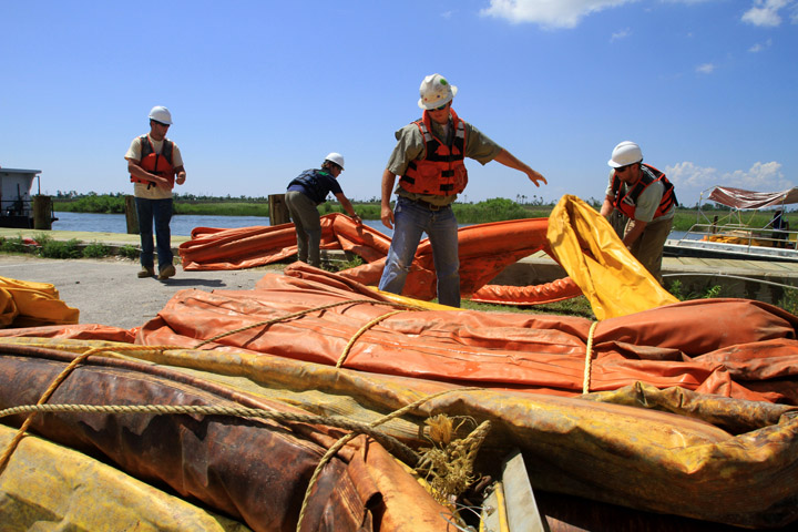 Workers with United States Environmental Services work with boom at Bayou Caddy in Hancock County as efforts continue to contain the oil spill in the Gulf of Mexico.