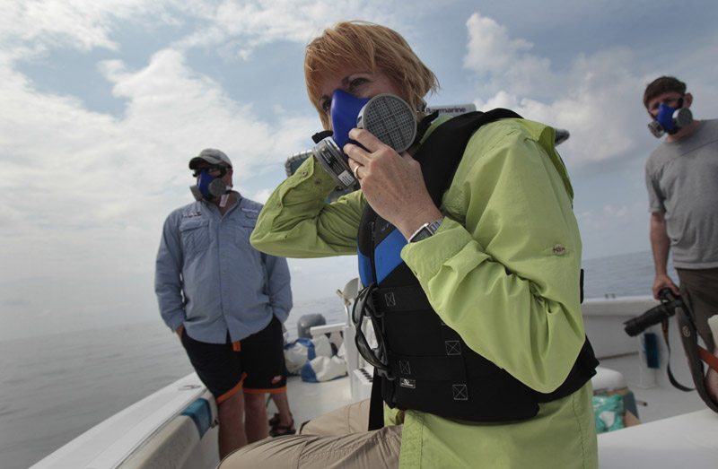 National Wildlife Federation program manager Maura Wood, center, wears a mask as she and her colleagues examine oil floating on the surface of the Gulf of Mexico near the coast of Louisiana today.