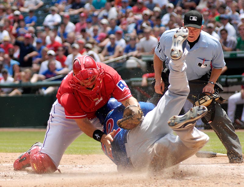 Rangers catcher Matt Treanor tries to tag Xavier Nady of the Cubs as umpire Jerry Meals watches in the sixth inning Sunday at Arlington, Texas. Nady was safe. The Cubs won 5-4.