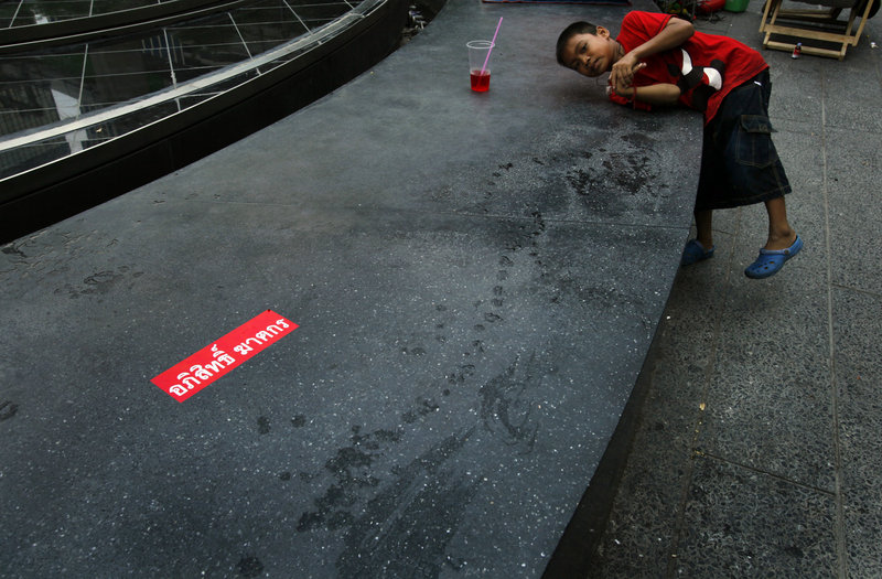 Despite the violence, a boy plays outside a closed upscale shopping mall in downtown Bangkok on Sunday.