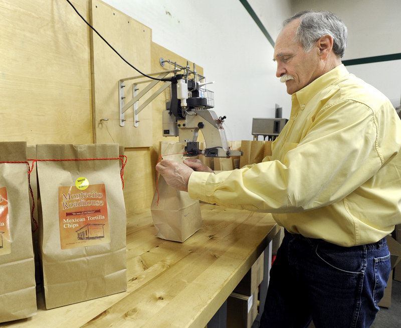Scott Rehart, owner of Montecito Roadhouse Inc. in Portland, applies the trademark red stitching to a bag of tortilla chips.