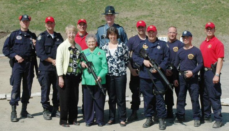 Rep. Paulette Beaudoin, D-Biddeford, holds a new AR-15 between Rep. Anne Haskell, D-Portland, and Public Safety Commissioner Anne Jordan. With them, from left, are Troopers John Davis and Lance McLeish, Sgt. William Keith, Col. Patrick Fleming, Troopers Andre Paradis and Jeff Degroot, Cpl. Ed Furtado and Troopers Eric Paquette and Jonathan Leach.