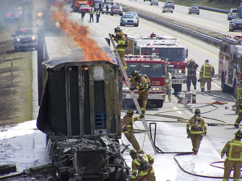 Firefighters work to extinguish the flames that consumed the cab of a tractor-trailer truck Friday afternoon near mile 17 on the Maine Turnpike in Wells. The fire apparently started in the engine compartment, but the cause is still undetermined.