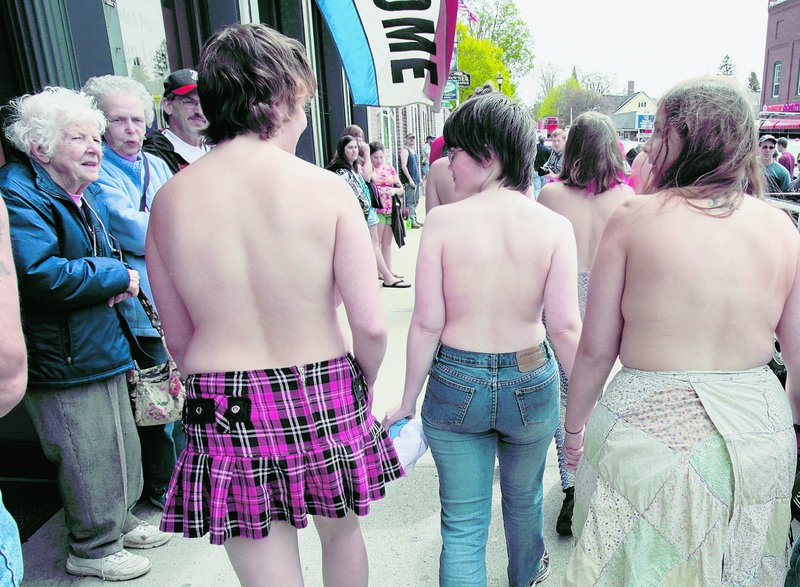 Topless women attract the attention of bystanders Friday in Farmington. In Maine, it's legal for women to go topless in public.