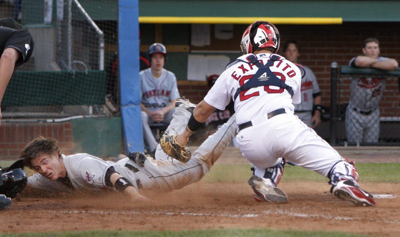 Joe Benson of New Britain dives by Sea Dogs catcher Luis Exposito to score in the second inning Friday night at Hadlock Field. Portland won, 13-4.