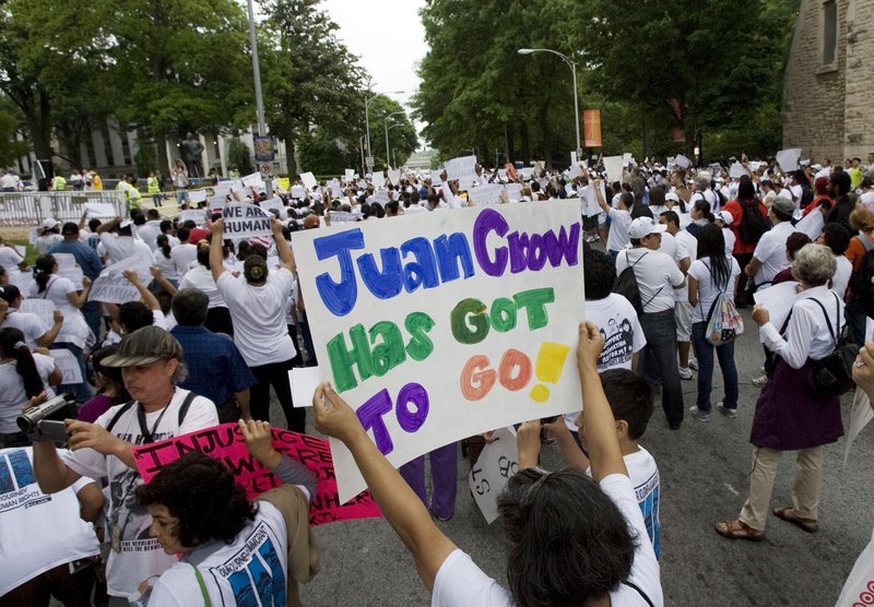 Marcia Molina of Marietta Ga., holds up a sign that reads Juan Crow has got to go during an immigration rally Saturday in Atlanta. The sign refers to so-called Jim Crow practices that discriminated against American blacks.