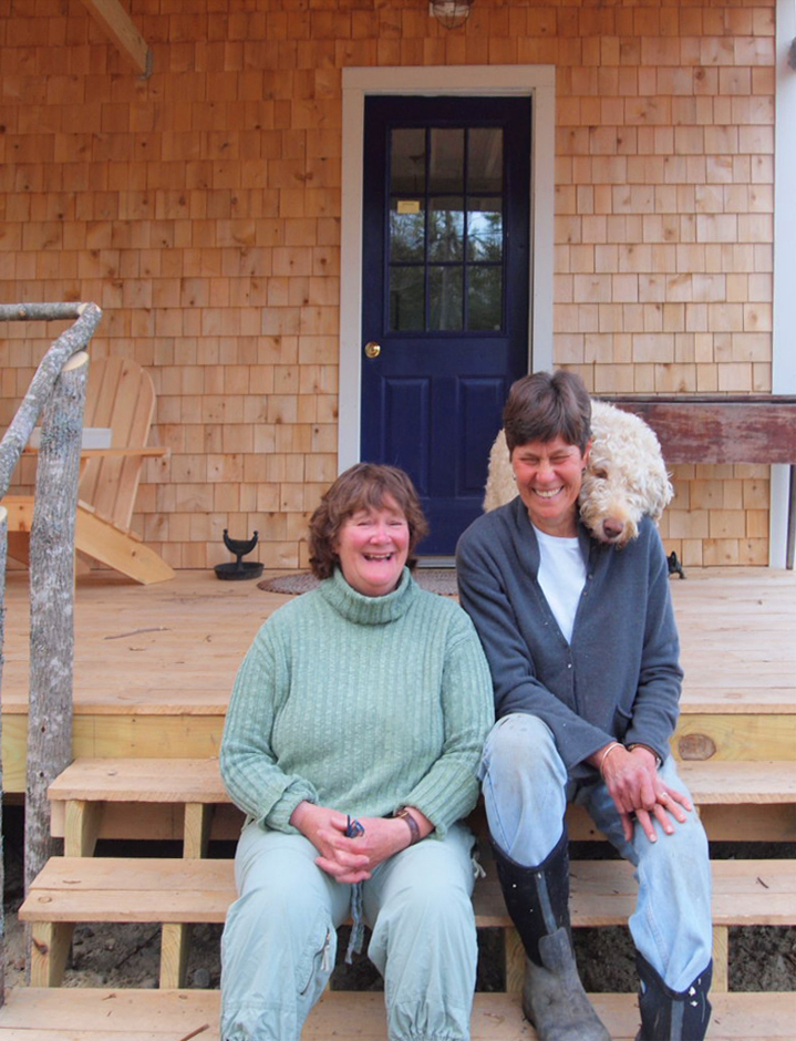 Partners Deede Montgomery and Kathy Heye, with Charlie the dog, sit on the steps of Bessie’s Farm Goods, which they built at 33 Litchfield Road in Freeport. The store opened Monday and will celebrate with a grand opening and sale of about 600 perennials this weekend.