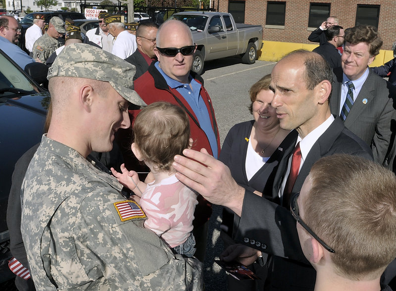 Gov. John Baldacci chats with Spc. Eric Madore and family as Army Reservists are given a grand send-off by family, friends and government officials Wednesday at the Army Reserve training center on Franklin Street in Saco. Behind Baldacci, Greg and Linda Madore enjoy the attention he is giving their son and the daughter of Eric’s fiancee, 18-month-old Savanna. Also in the group of well-wishers are fiancee Katie Wildes, on Eric’s left, and Adam Madore, 16, in right foreground. State Sen. Barry Hobbins watches at right.