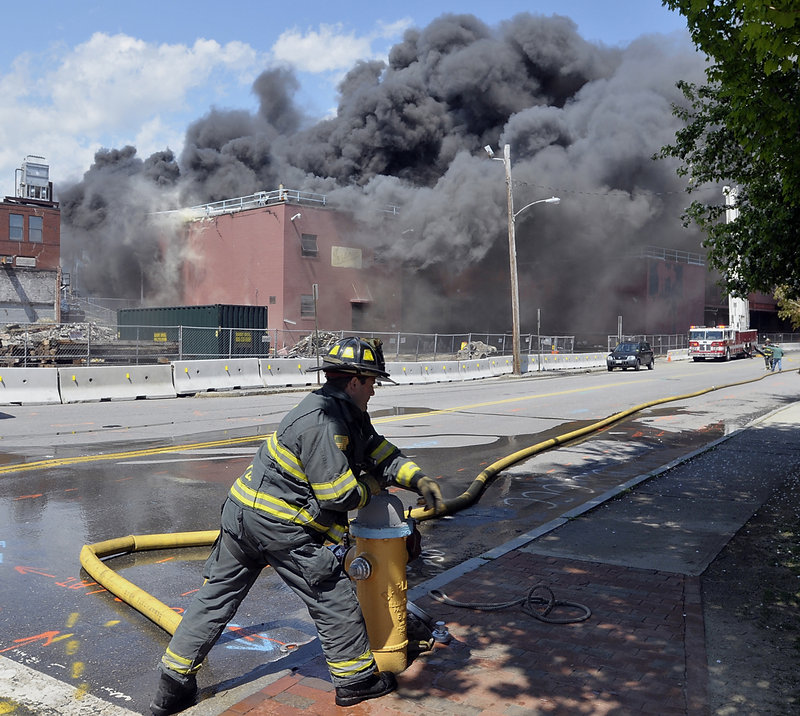 A Portland firefighter turns on a hydrant at Franklin and Fore streets to add water to the fire at the former Jordan’s Meats building Thursday. About 100 firefighters battled the blaze, which broke out around 1:30 p.m.