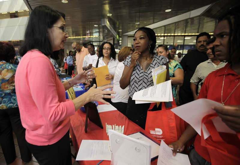 Nancy Rosello, left, an employment coordinator with Spectrum Programs Inc., talks with job seekers Thursday at a fair hosted by the Miami-Dade Community Action Agency in Miami. First-time claims for unemployment benefits dropped last week for the third straight time.