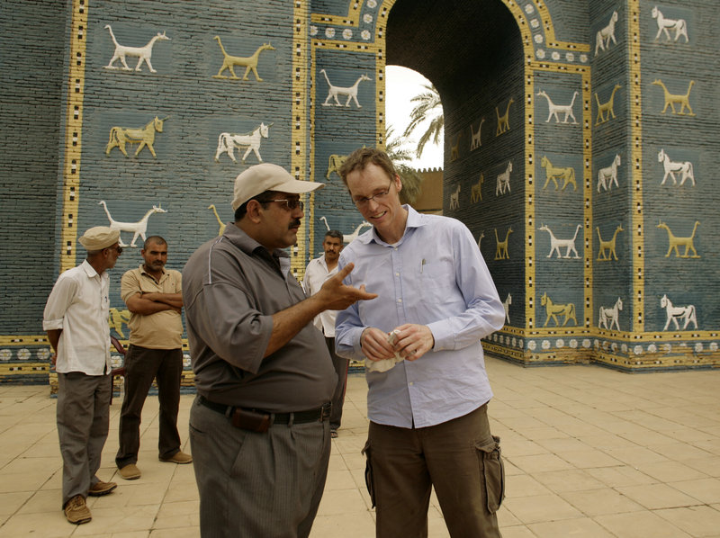 Jeffrey Allen, right, co-coordinator of a U.S.-funded project to restore the ancient city of Babylon, talks to guide Mohammed Taher outside a reproduction of the Ishtar gate at the site. Iraqi officials are at odds over keeping the site authentic or making money off it.