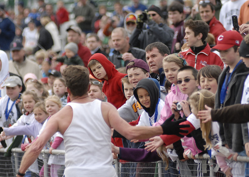 A runner gets high-fives from spectators as he approaches the finish line inside Hadlock Field.