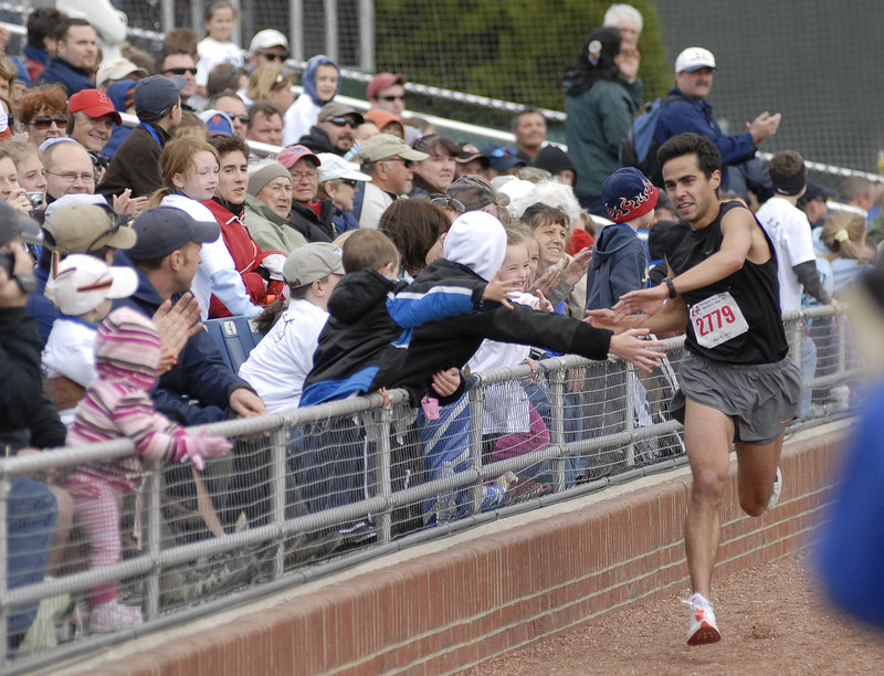 Louie Luchini of Ellsworth is greeted by youngsters as he approaches the finish line Sunday as the winner of the Sea Dogs Mother's Day 5K.