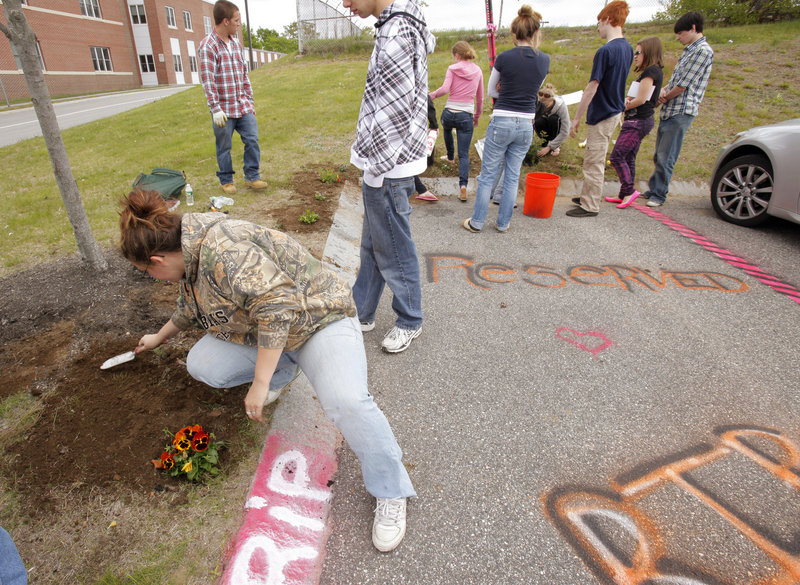 Ashley Morse, a senior at Scarborough High School, plants flowers Monday around a parking space at the school where senior Steven Delano always parked. Delano was killed in a car crash Saturday on his way to the Gorham High School prom with three other teenagers.