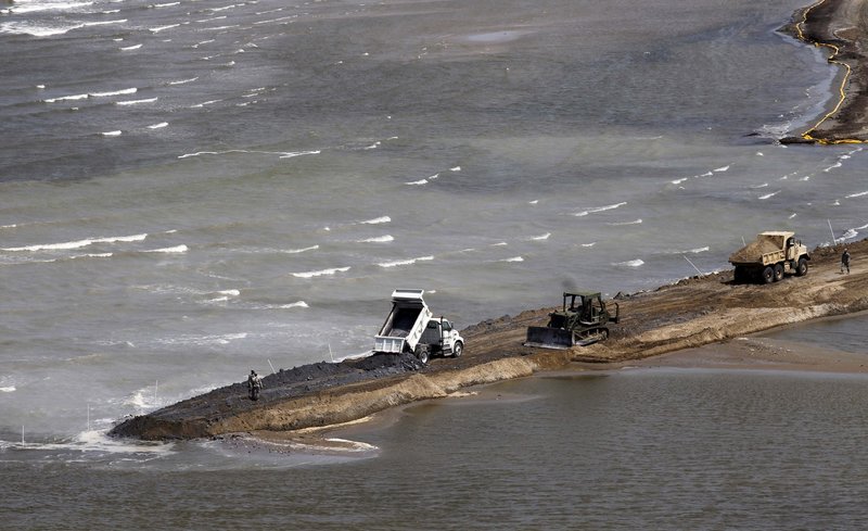 National Guard dump trucks, front-end loaders and backhoes dam off part of the marsh on Elmer’s Island in Grand Isle, La., on Monday. Oil is still pouring into the Gulf of Mexico at a rate of about 210,000 gallons per day. At least 4 million gallons are believed to have leaked since an April 20 drilling rig explosion killed 11 workers.