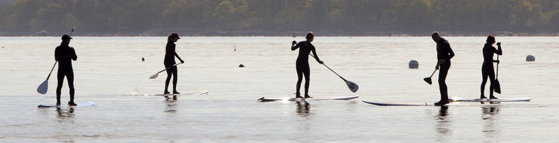 People travel by paddleboard across Casco Bay after attending a protest against offshore drilling on East End Beach in Portland on Wednesday.