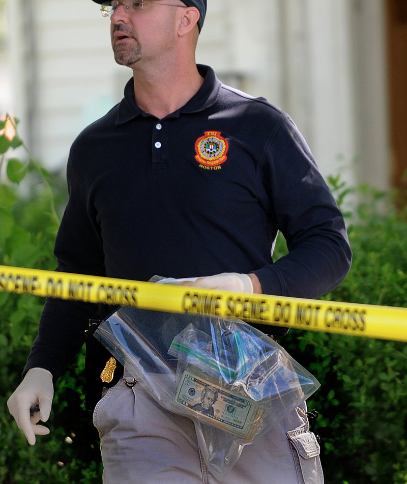 An FBI investigator carries a bag containing money as he departs a house at 39 Waverley Avenue in Watertown, Mass. The FBI raided the house early Thursday in connection with the failed car bomb attempt in New York City’s Times Square.