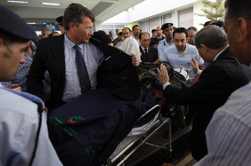 Police officers and medical officials shield 9-year-old Ruben van Assouw from the media as he leaves the hospital Saturday in Tripoli, Libya, for the flight home to the Netherlands. The boy, the sole survivor of Wednesday's Afriqiyah Airways crash, suffered two broken legs.