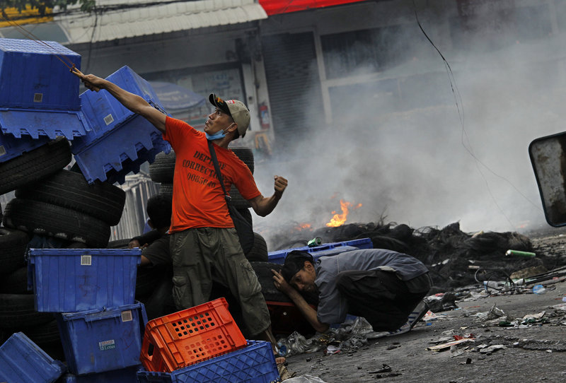 An anti-government protester fires a slingshot at Thai soldiers on Sunday in Bangkok, Thailand. About 30 civilians have been killed in the last four days, and about 59 since March.