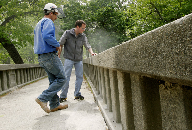 Scott Bourgoin, left, of Gorham-based Knowles Industrial Services, and Scott Hawk of Woodard & Curran in Portland discuss rehabilitation options for the footbridge in Portland's Deering Oaks on Tuesday.