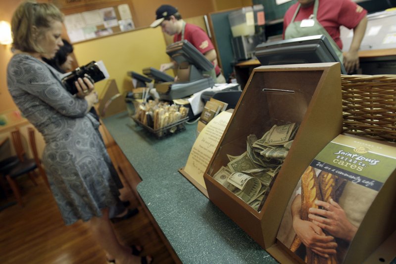 Customers order food as a cash box sits on the counter at Panera Bread in Clayton, Mo. The national bakery and restaurant chain’s new nonprofit store allows customers to donate what they want for a meal.