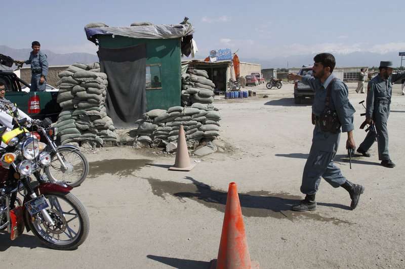An Afghan police officer stops motorbikes Wednesday near the U.S.-run Bagram Airfield, where insurgents launched a brazen predawn assault with gunfire, rockets and grenades.