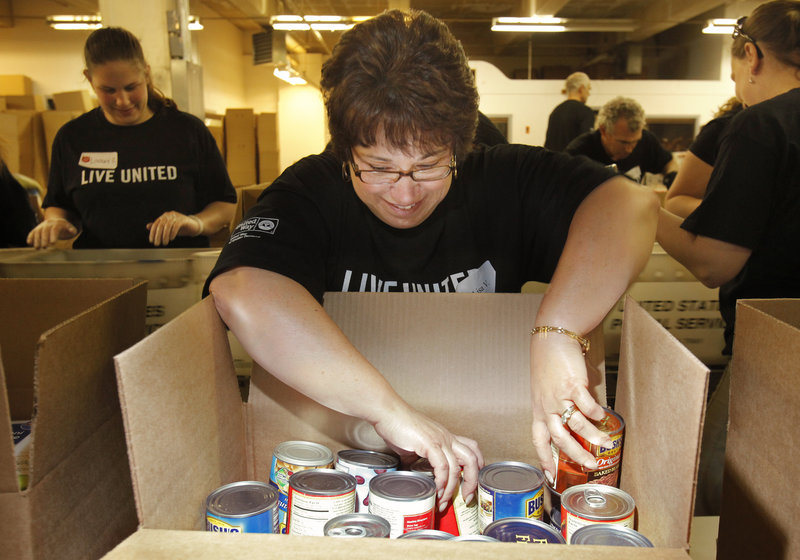 Gregory Rec/Staff Photographer Lisa Varela sorts canned goods while participating in the United Way Day of Caring in Portland on Thursday. The volunteers at this location sorted about 50,000 pounds of food gathered by The National Association of Letter Carriers  canned goods that the Salvation Army will in turn distribute to Portland-area food pantries.