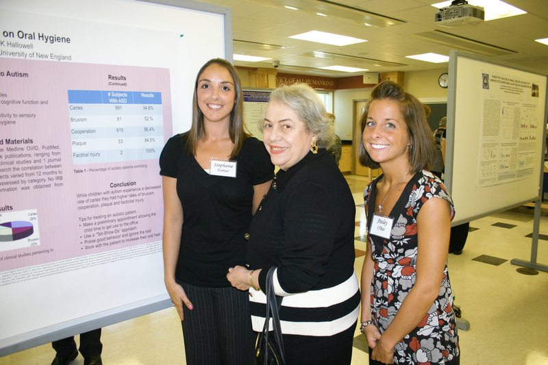 Past UNE President Sandra Featherman chats with recent dental hygiene graduates Stephanie Fortier and Ansley O’Bar, who presented their research about autism’s impact on dental hygiene.