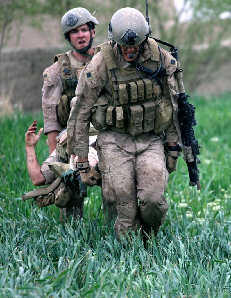 U.S. Marines carry a wounded fellow Marine across a field to a waiting Army Task Force Pegasus medevac helicopter during a firefight in Helmand province in Afghanistan.