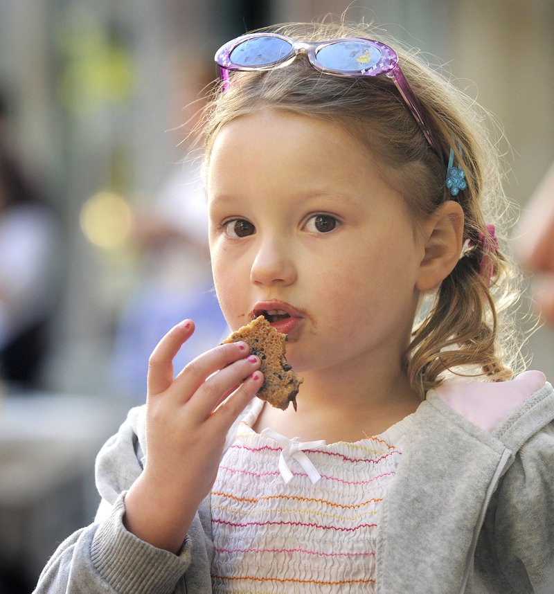 Three-year-old Isabelle Litalien of Belgrade enjoys a piece of a cookie pizza made by the Sweet Love shop during Hogs, Pies and Fireworks on Friday in Gardiner.