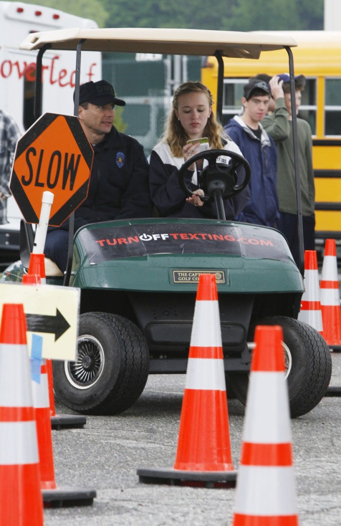 In this May 6, 2010 photo, Capt. Drew Bloom of the Vermont Department of Motor Vehicles, left, rides along with 10th-grader Hannah Chambers during a texting-while-driving event in White River Junction, Vt. While states pass laws banning texting while driving, some are going a step further, giving kids first-hand experience of the dangers of sending electronic messages while behind the wheel. They're sending kids through obstacle courses on golf carts while texting, keeping track of how many errors and fatalities they may cause.