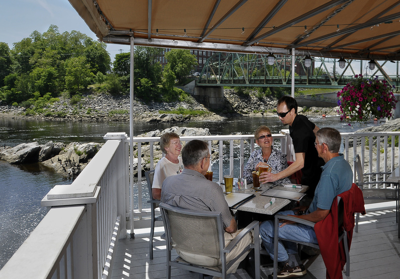 Shon Rivera, waiter at the Sea Dog Brewing Co. in Topsham, serves beverages to Jack and Judy Bauman of Brunswick and their friends Paula and Glenn Gipson. The deck has great views of the Androscoggin River.