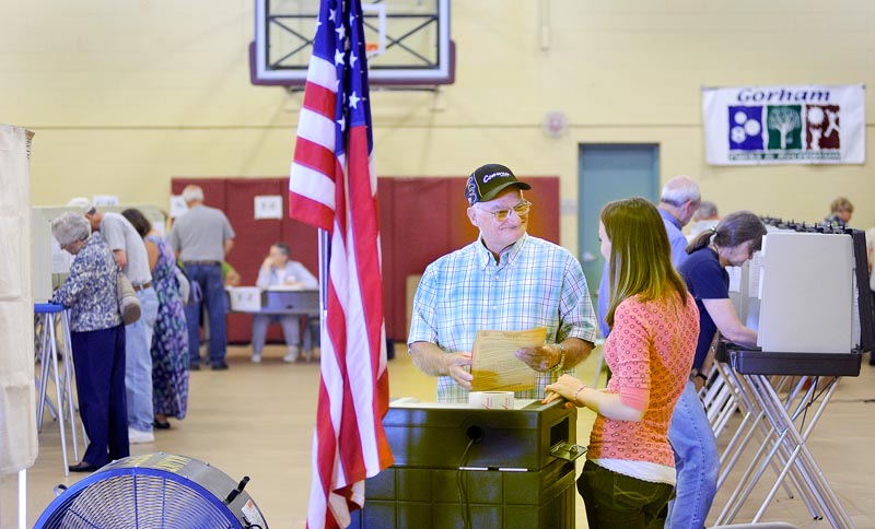 Richard Moody shares a light moment with ballot clerk Melissa Deering as he casts his votes in the Gorham Municipal Center today. (John Patriquin /Staff Photographer)