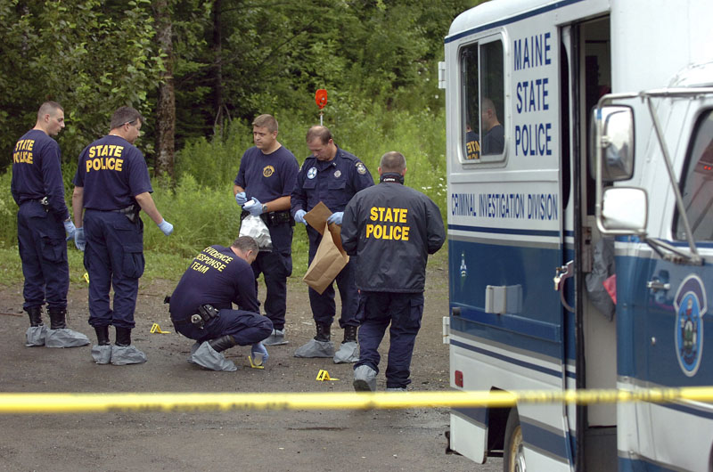 Maine State Police Evidence Response Team members investigate the scene of a triple homicide in Amity.