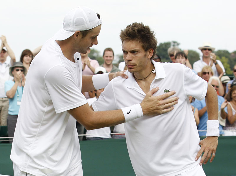 American John Isner, left, consoles France's Nicolas Mahut at the end of their epic men's singles match at the All England Lawn Tennis Championships at Wimbledon today.