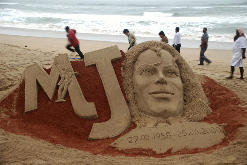 People walk past a sand sculpture of Michael Jackson created to mark the first anniversary of his death, at the Bay of Bengal coast, in Puri, Orissa state, India, Thursday.
