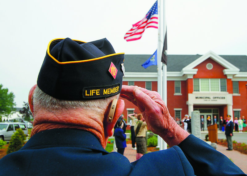 Gilbert Ormsby, a veteran of the Korean War, salutes as the American flag is raised at Topsham Town Hall on Monday.