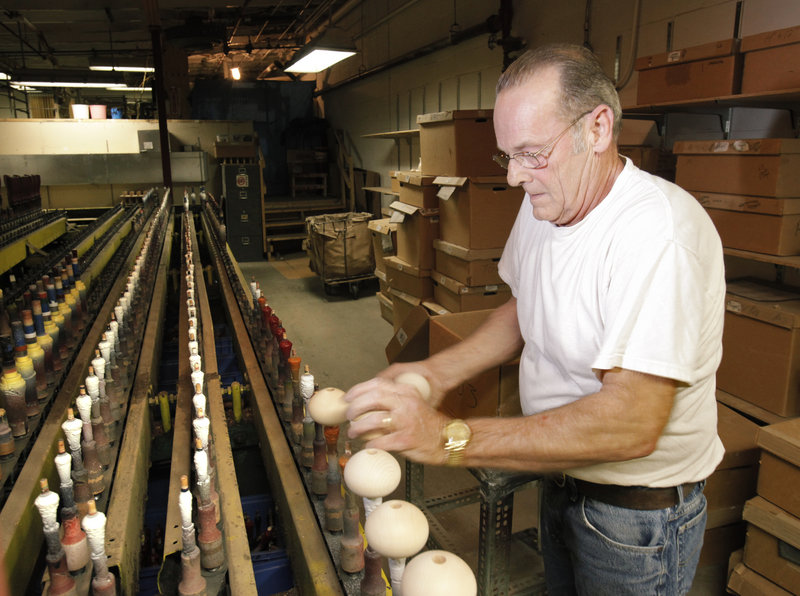 Neil Evans puts pepper-grinder tops on spindles that will run them through a painting machine at the Vic Firth factory.