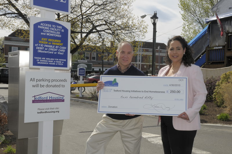 Larissa Darcy, vice president of Savings Bank of Maine, presents Don Kniseley, executive director of Tedford Housing, with a $250 check, the proceeds from the bank’s Brunswick parking area.