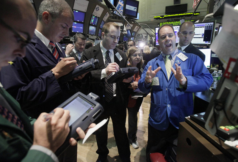 Specialist Thomas Warshaw, foreground right, directs trades in shares of BP on the floor of the New York Stock Exchange. Led by BP’s stock plunge, the Dow lost 112 points Tuesday.
