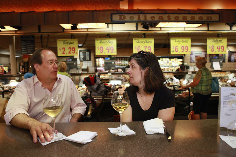 George Hruby, left, and his wife, Alison Hruby, of Fairfax, Va., enjoy a glass of wine at the delicatessen inside the Market Cafe in the Wegmans grocery store in Fairfax, Va. Supermarkets are hoping customers will grocery shop, of course, but also stop more often for a low-cost restaurant-style meal.