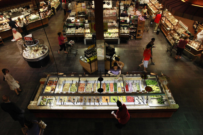 Customers shop at the salad bar for lunch at the Market Cafe in the Wegmans grocery store in Fairfax, Va. The prepared supermarket food available today is a far cry from the modest offerings of fresh coffee, potato salad and rotisserie chickens of years past, as grocery stores try to increase their appeal and customer traffic.