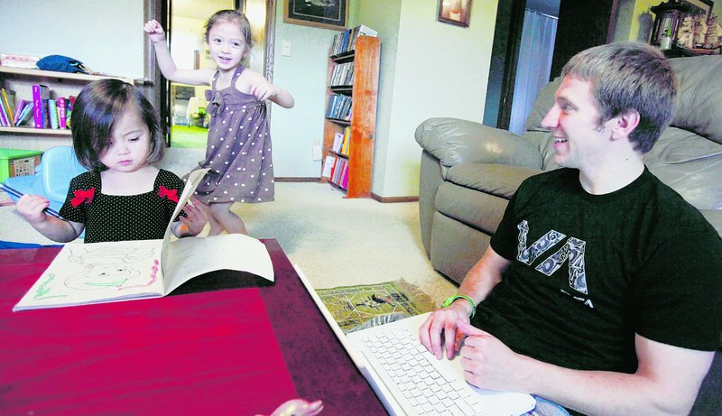 John Kay, a recent graduate of Pepperdine Law School, plays with his daughters Hana, left, and Autumn, while looking for jobs online. Kay had a job offer, but it was rescinded due to the sour economy.