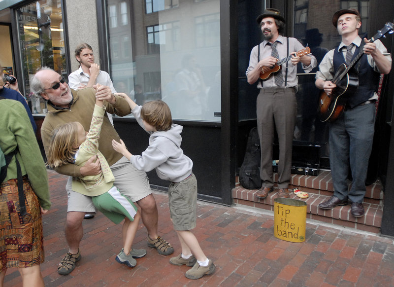 Scott Elliott of Portland dances with Carly Hagelin, 8, of Portland and his son Kieran Elliott, 7, as Tim Findler and Jimmy Dority of Portland perform on Congress Street during the First Friday Art Walk on Friday. Findler is playing a ukulele as Dority plays the tenor guitar.