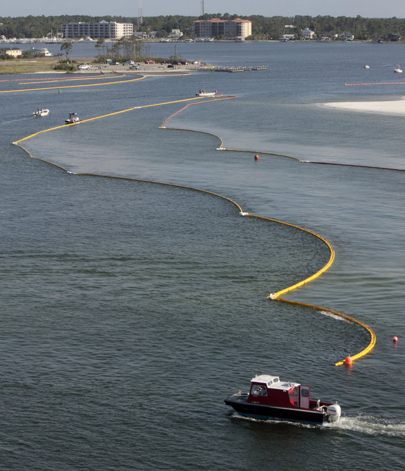 Boats work to secure oil containment booms in the Perdido Pass in Orange Beach, Ala., on Friday. Oil from the Deepwater Horizon oil drilling blowout and explosion that killed 11 workers on April 20 has started washing ashore on Alabama and Florida coast beaches.