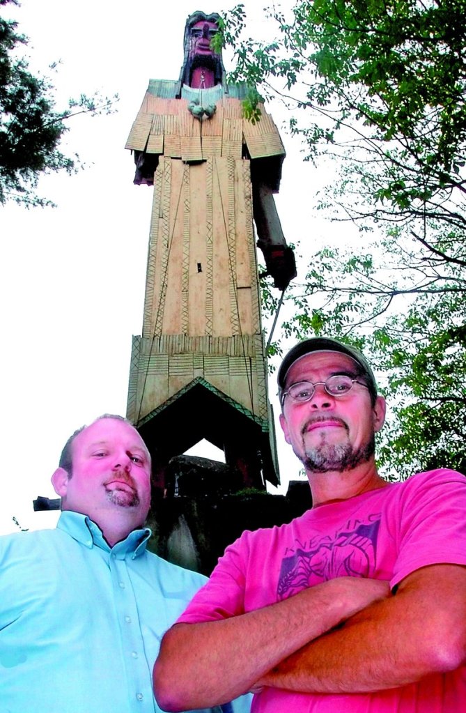 Cory King, left, executive director of the Skowhegan Area Chamber of Commerce, and cabinet maker Stephen Dionne pose beneath Bernard Langlais’ Indian. Parts of the sculpture have been removed for restoration, which is Dionne’s bailiwick.