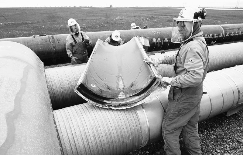 BP workers remove insulation from a pipeline at the Prudhoe Bay oil field on Alaska’s North Slope in August 2006 so that the pipe can be ultrasound-tested for weakness due to corrosion. Five months earlier, 200,000 gallons of oil spilled from a hole in the pipeline.