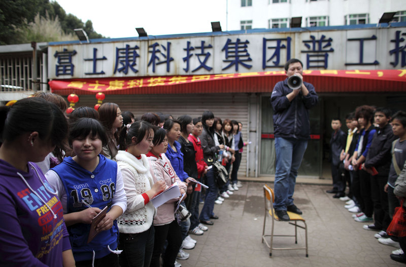 A recruiter talks to job seekers near a sign which reads “Foxconn Technology Group Recruitment Point” in Shenzhen, China. The firm has increased pay by up to 65 percent at its factories in Shenzhen.