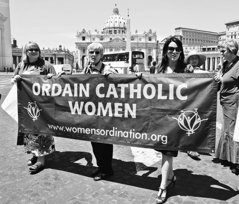 Representatives of the Women’s Ordination Conference protest Tuesday in front of St. Peter’s Basilica in Rome, with, from left, Therese Koturbash of Dauphin, Manitoba, Mary Ann Schoettly of Newton, N.J., and Erin Saiz Hanna of Washington, D.C. The protest took place on the eve of a rally marking the end of the Catholic Church’s yearlong celebration of the priest.